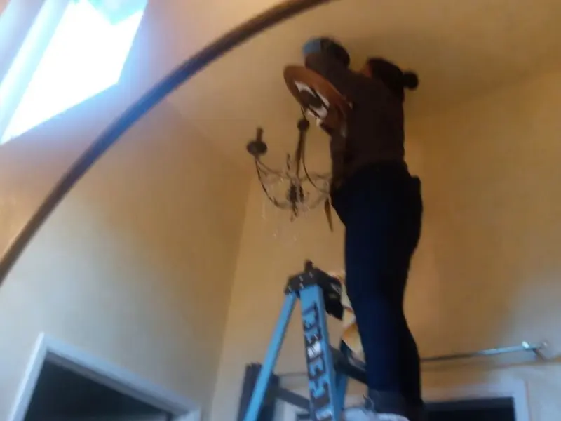 Electrician installing a chandelier in a Jacksonville residence